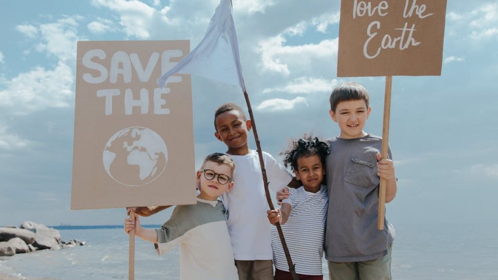 Group of diverse kids holding environmental awareness signs on a beach, spreading a message of saving the Earth.
